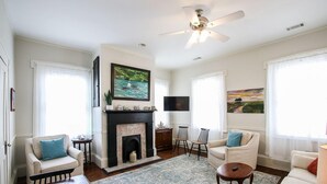 A spacious living room with a fireplace, two armchairs, a sofa, a flat-screen TV, and artwork on the walls. - Artist's House Upper Apt Walk to Forsyth (Savannah)