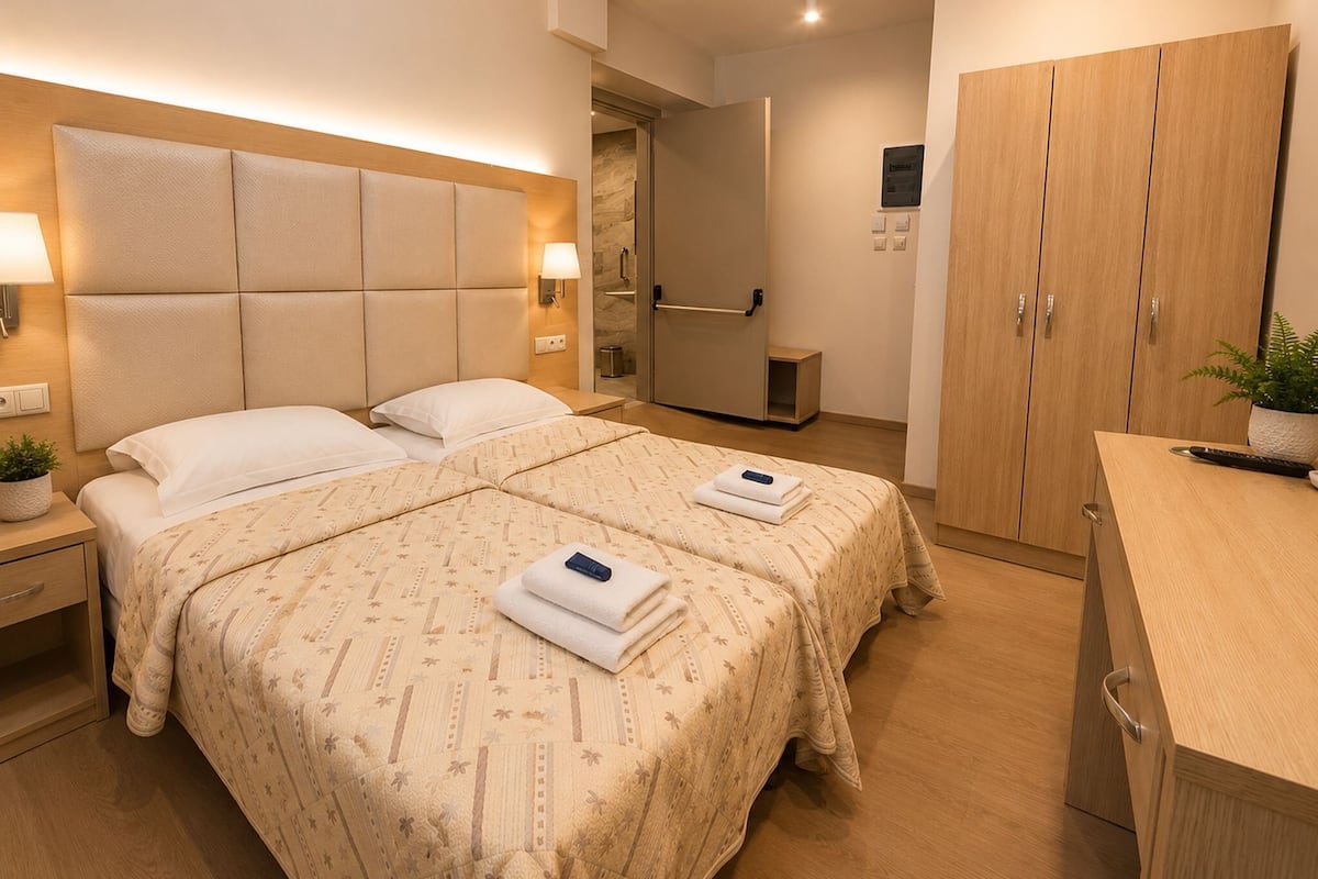 A hotel room with a large bed, bedside tables, a wardrobe, and a bathroom.