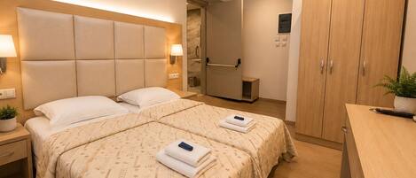 A hotel room with a large bed, bedside tables, a wardrobe, and a bathroom.