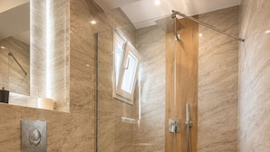 A modern bathroom with a glass-enclosed shower, a wooden vanity, and a marble-tiled wall. - Avra Hotel (Thermaikos)