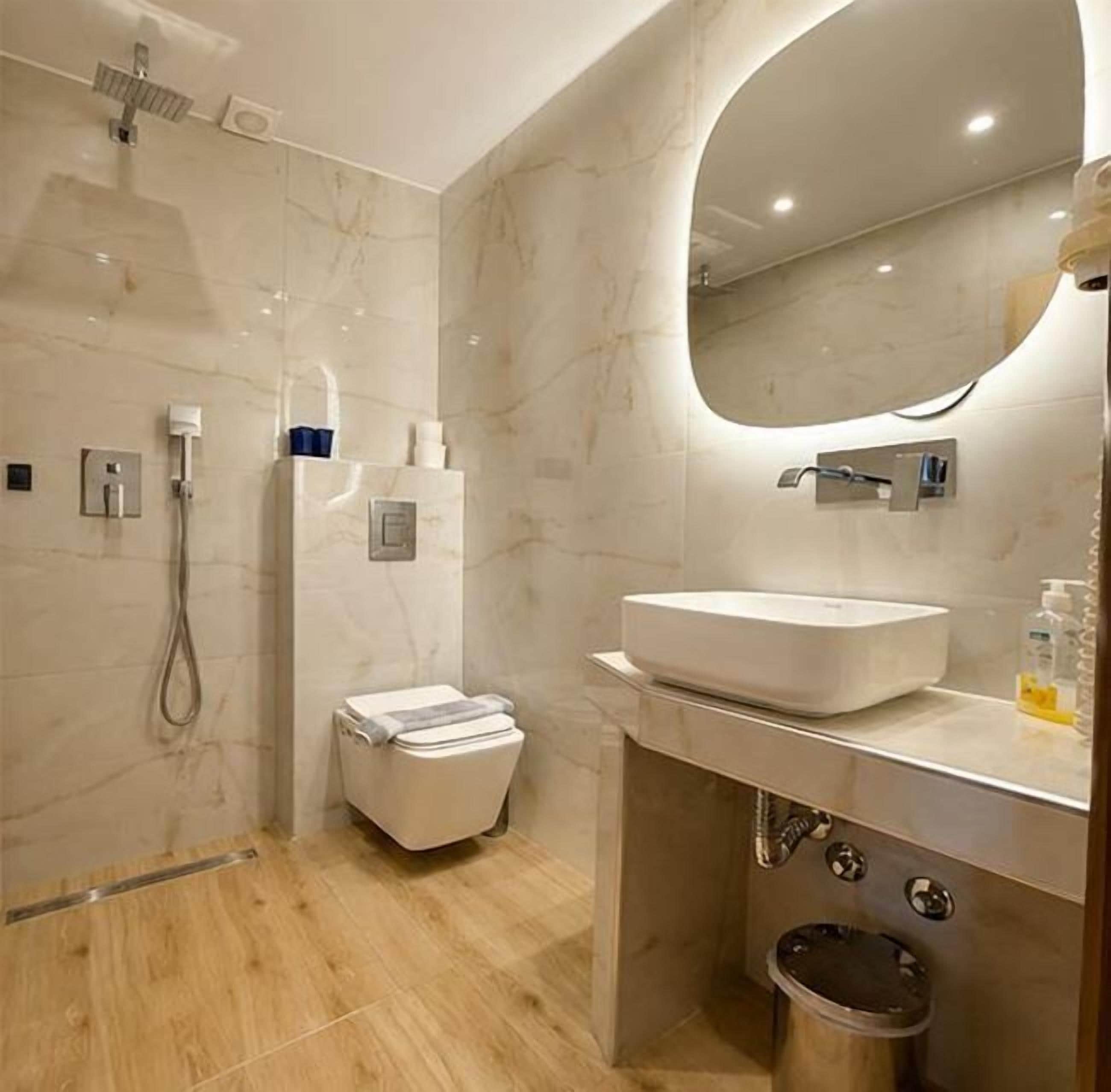 A modern bathroom with a shower, toilet, sink, and mirror.