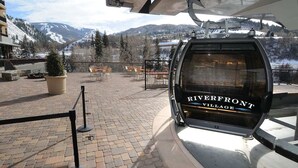 A cable car at Riverfront Village with a view of snow-covered mountains.