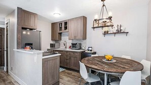 A modern kitchen with wooden cabinets, a central island, and a dining area with a round table and chairs.