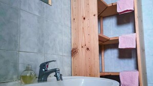 Ein Badezimmer mit weißem Waschbecken, einem Spiegel und einem Holzboden mit rosa Handtüchern.
