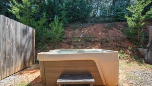 A hot tub with a wooden bench in front, surrounded by a wooden fence and trees. - Peaceful Getaway, Sleeps 6・Hot Tub (Sevierville)