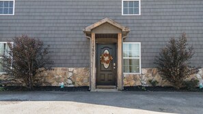 A house with a stone foundation, a dark brown front door, and a stone wall. - Sevierville Family Retreat with Private Hot Tub and Mountain Fun (Sevierville)