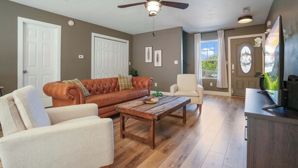 A living room with a brown leather sofa, a wooden coffee table, a beige armchair, and a ceiling fan. - Peaceful Getaway, Sleeps 6・Hot Tub (Sevierville)