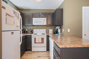 A compact kitchen with a refrigerator, microwave, stove, and a coffee maker. - Sevierville Family Retreat with Private Hot Tub and Mountain Fun (Sevierville)