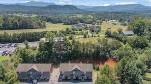 A residential area with two large houses, a parking lot, and a view of distant mountains. - Sevierville Family Retreat with Private Hot Tub and Mountain Fun (Sevierville)