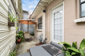 A small outdoor patio area with a table and chairs, a potted plant, and a welcome mat. - The Belle Aire - Hist District Savannah (Savannah)