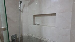 A modern bathroom with a glass shower enclosure, a built-in shelf, and a marble floor. - Arianna Dhangethi (Dhangethi)
