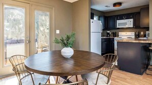 A kitchen with dark cabinets, a white refrigerator, and a round wooden table with chairs. - Peaceful Getaway, Sleeps 6・Pet Friendly & Hot Tub (Sevierville)
