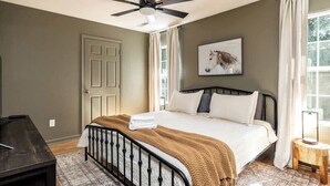 A bedroom with a bed, a ceiling fan, a door, and a window with curtains. - Peaceful Getaway, Sleeps 6・Pet Friendly & Hot Tub (Sevierville)