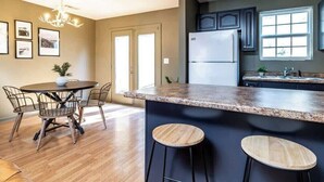 A modern kitchen with a granite countertop, stainless steel appliances, and a dining area with a round table and chairs. - Peaceful Getaway, Sleeps 6・Pet Friendly & Hot Tub (Sevierville)