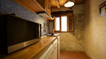 Una cocina con armarios de madera, microondas, pileta y ventana.