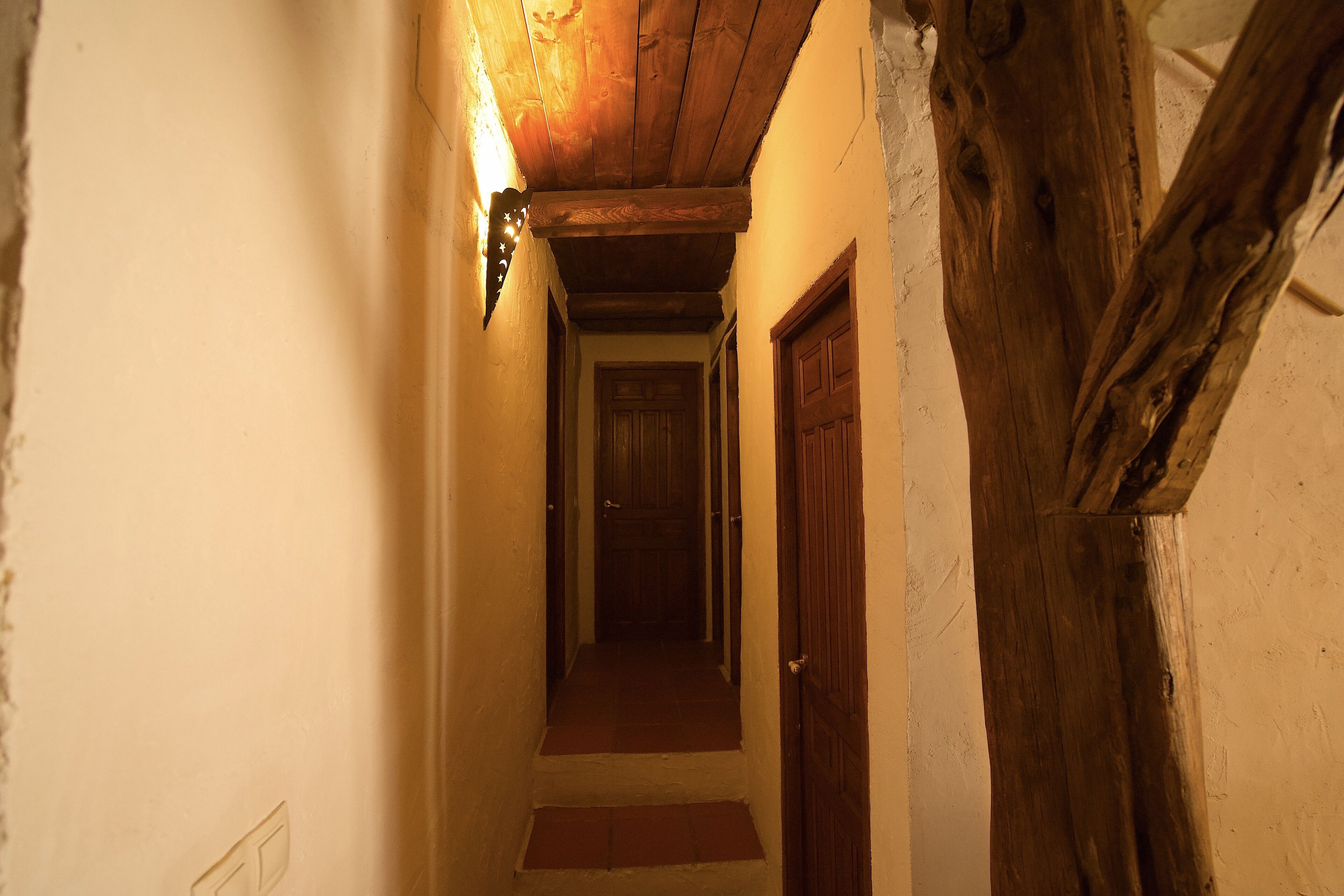 Un pasillo estrecho con vigas de madera y una puerta de madera al final.