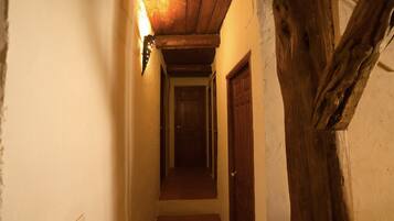 Un pasillo estrecho con vigas de madera y una puerta de madera al final.