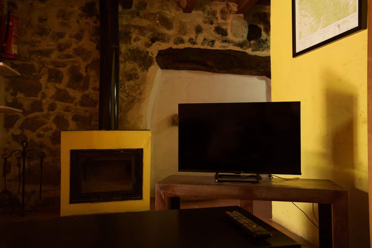 Ein Zimmer mit Steinwand, Kamin und Fernseher auf einem Holzbalken.