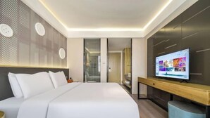 A modern hotel room with a large bed, a TV on a wooden console, and a walk-in closet. - Jin Ri Ming Du Hotel (Lanxi)