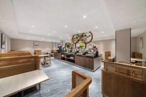 A hotel lobby with seating areas, a reception desk, and a decorative wall.