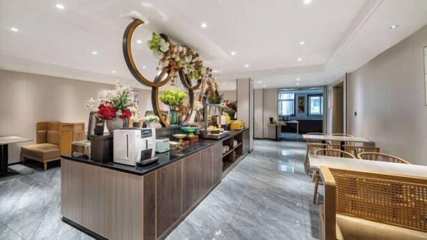A modern hotel lobby with a reception desk, seating area, and a view into the dining area. - Jin Ri Ming Du Hotel (Lanxi)