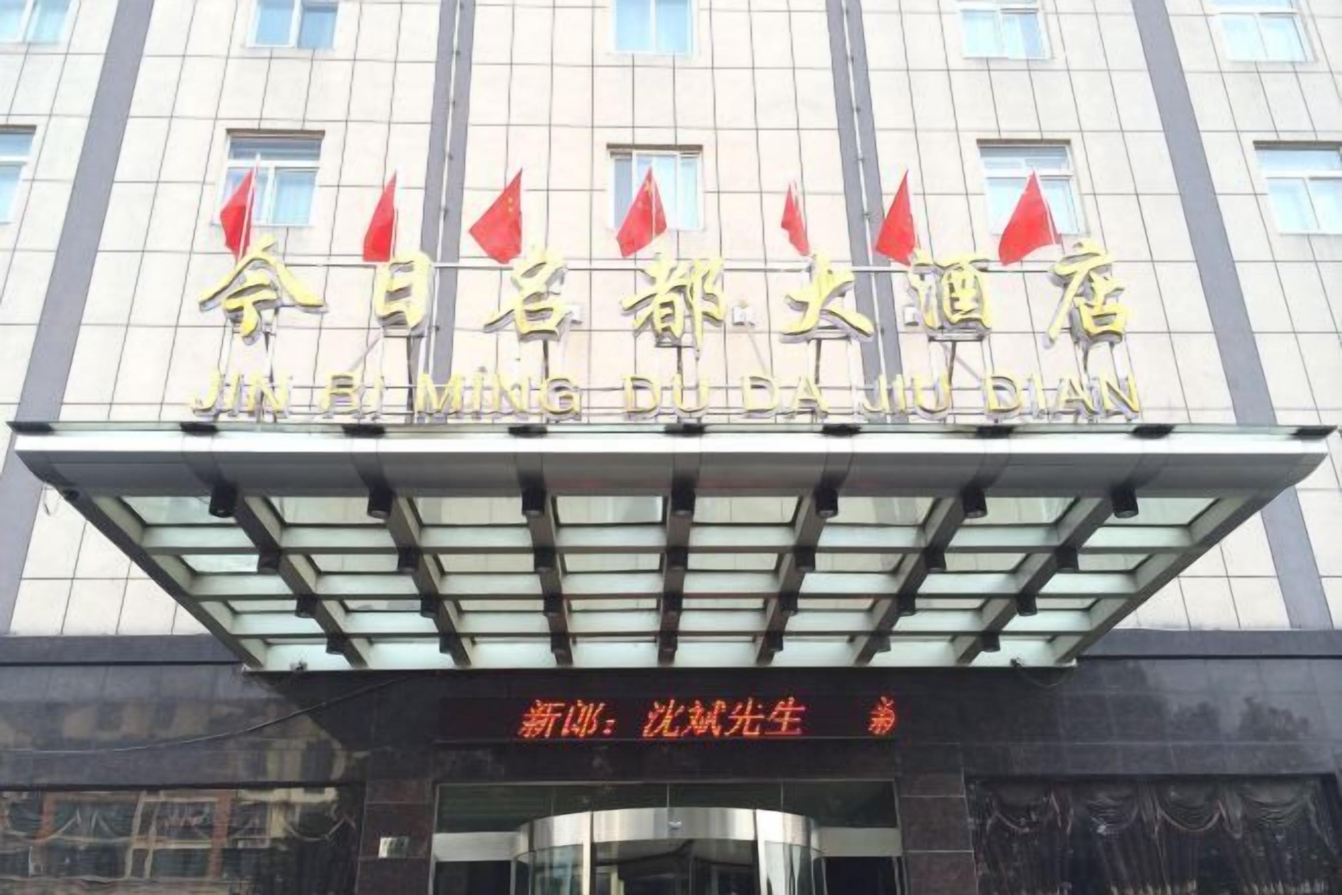 A hotel with a modern facade, featuring a prominent sign with Chinese characters and red flags.