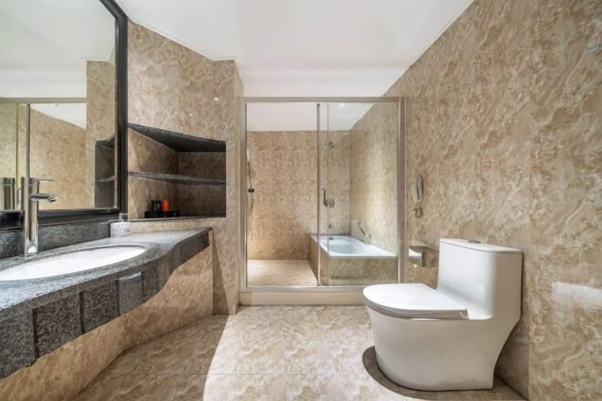 A modern bathroom with a curved sink, a glass-enclosed shower, and a white toilet.
