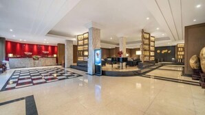 A spacious lobby with a checkered floor, a reception desk, and a seating area. - Jin Ri Ming Du Hotel (Lanxi)