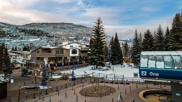 A ski resort with a large building, possibly a lodge, surrounded by snow-covered trees and a mountain backdrop.