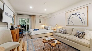 Una habitación de hotel con cama, sofá, escritorio y televisión.