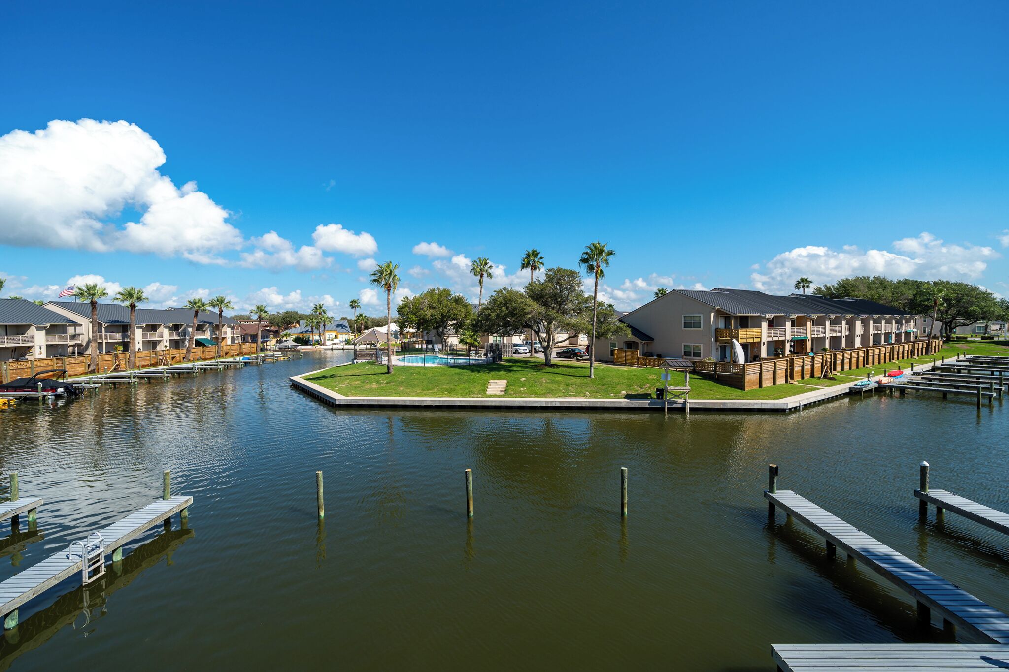 A waterfront hotel with a pool, docked boats, and a clear view of the water.