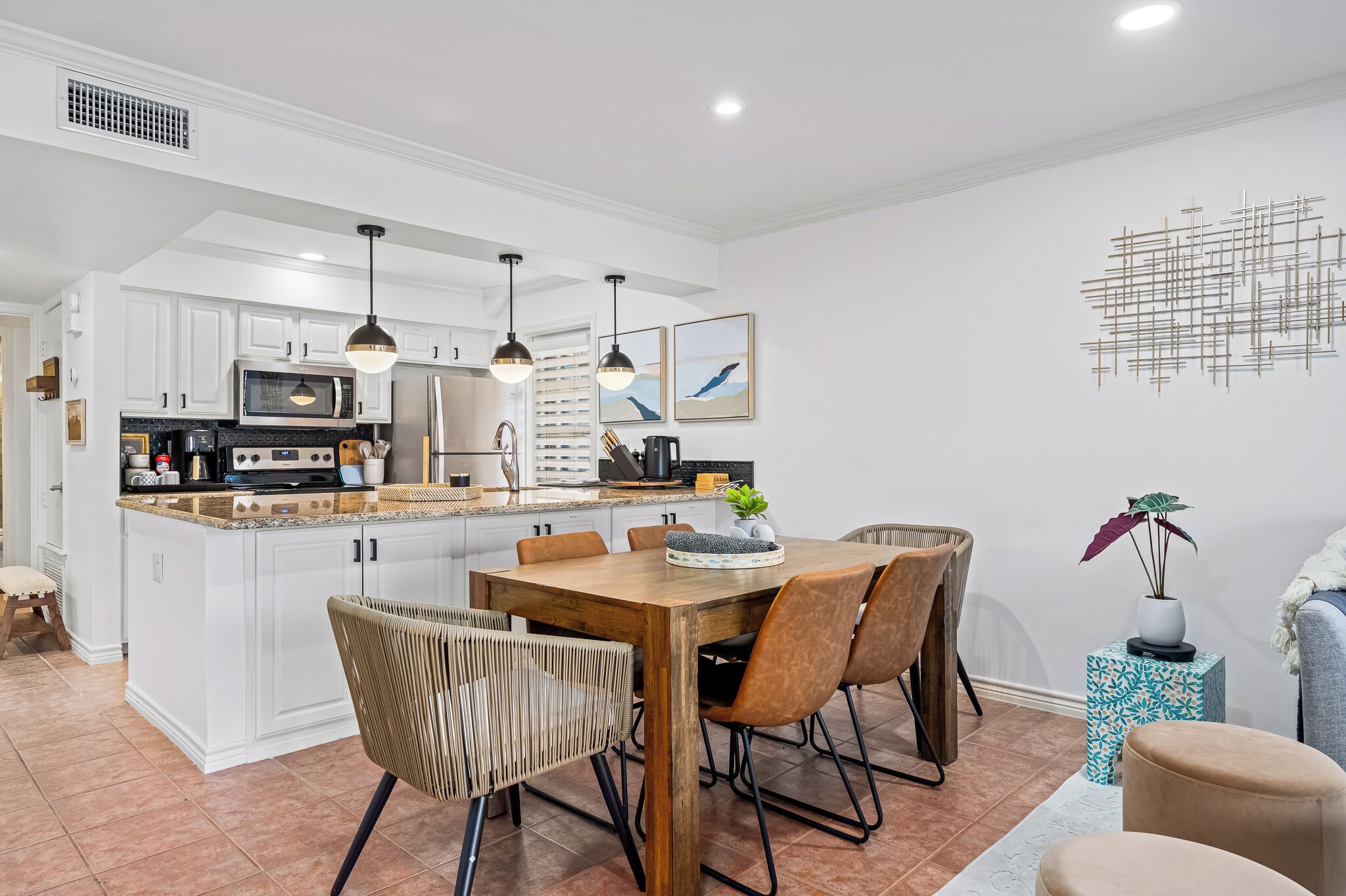 Una cocina moderna con armarios blancos, una isla central e iluminación colgante.