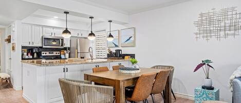 Una cocina moderna con armarios blancos, una isla central e iluminación colgante.