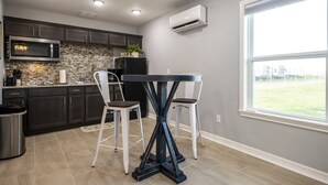 Een moderne keuken met donkere kastjes, een betegelde achterwand, een ingebouwde magnetron en een groot raam met uitzicht op de omgeving.