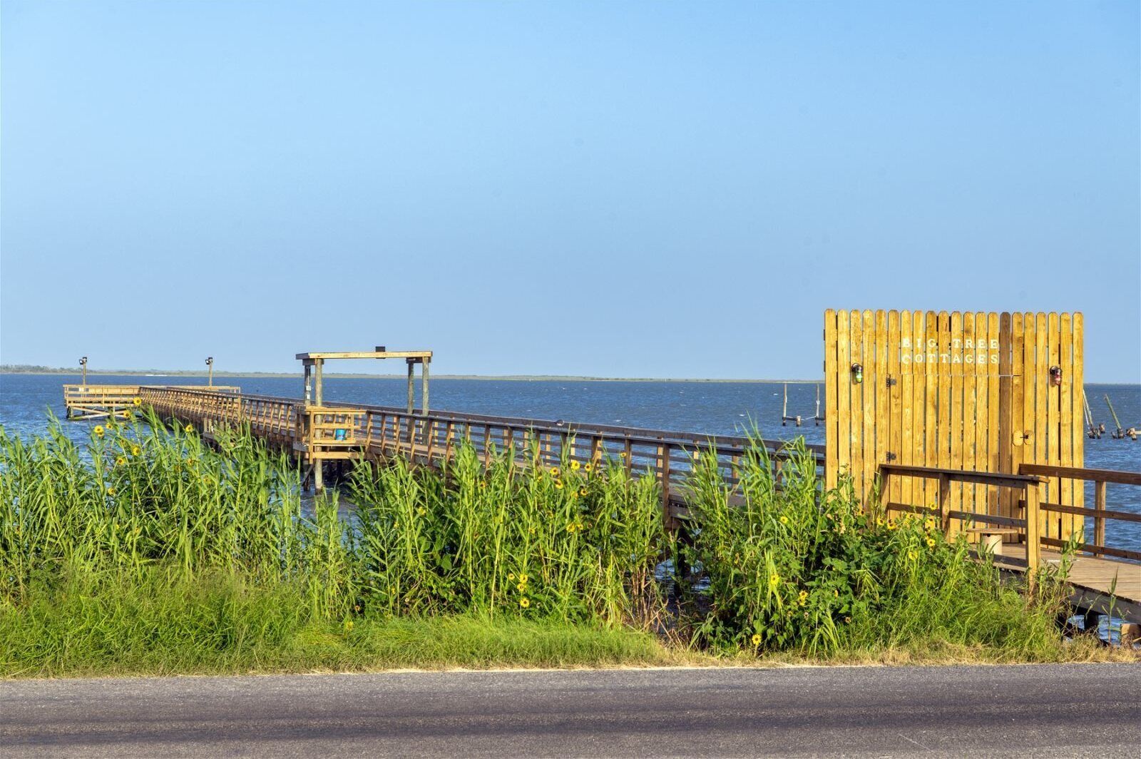 A wooden pier extending into a body of water, with a wooden structure labeled "BIG TREE COTTAGES" on the right.