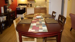 A dining table with a patchwork table runner, surrounded by wooden chairs.