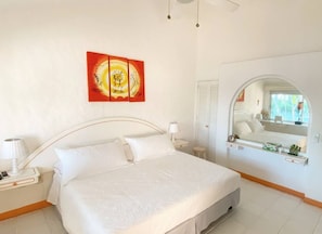 A bedroom with a bed, a nightstand, a lamp, a mirror, and a window. - Amazing Villa in Ixtapa (Troncones)
