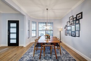 Un coin repas avec une table en bois, des chaises, un lustre et un tapis à motifs bleus.