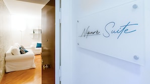 Placa de hotel com a inscrição 'Nipare Suite' em um quarto moderno e bem iluminado, com um sofá branco e uma luminária.