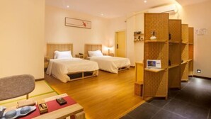 Une chambre d’hôtel avec deux lits, un bureau en bois et un petit coin salon.