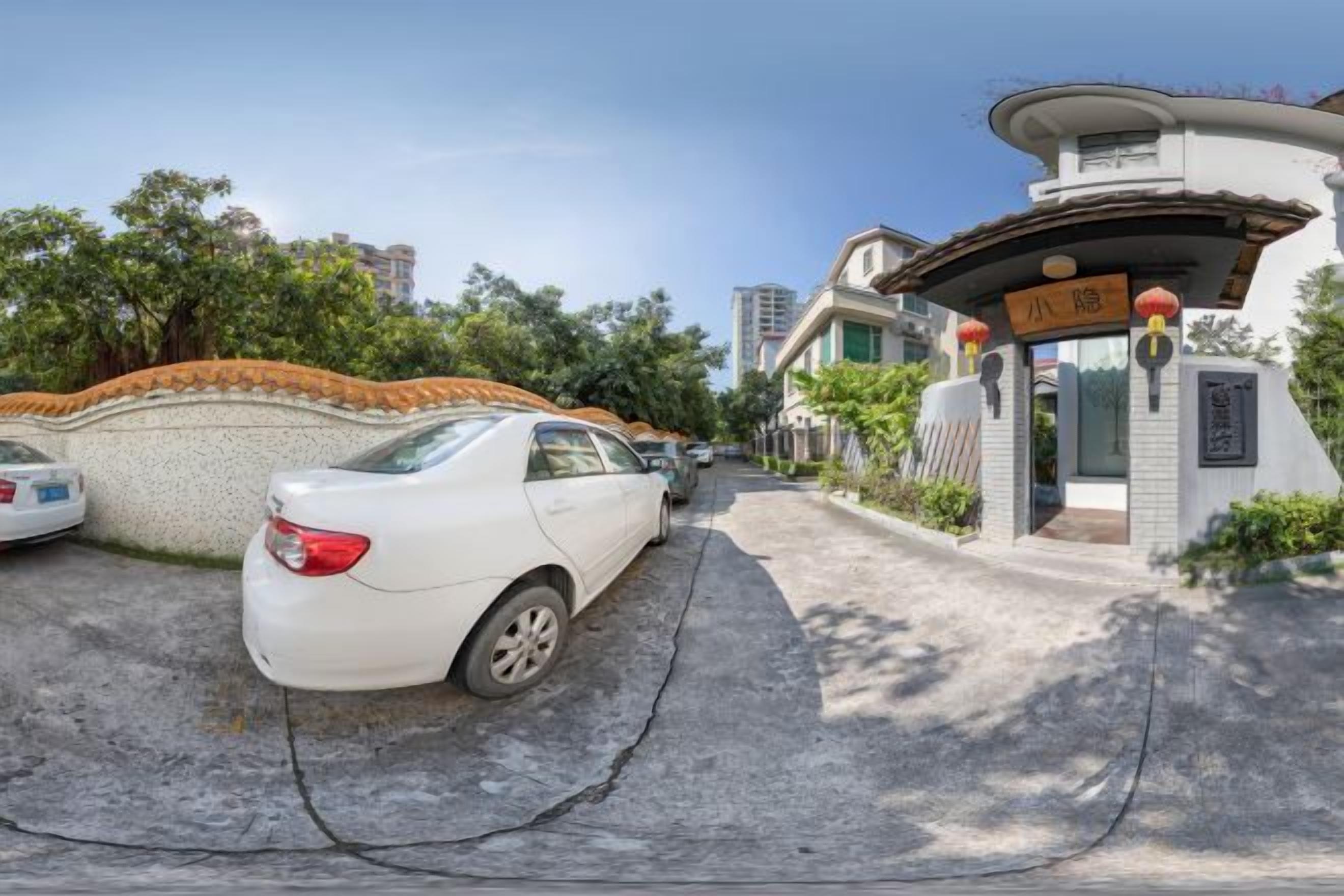 Un cancello chiuso all'ingresso di una zona residenziale, con un'auto bianca parcheggiata nel vialetto.