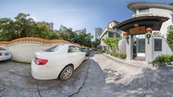 Un cancello chiuso all'ingresso di una zona residenziale, con un'auto bianca parcheggiata nel vialetto.