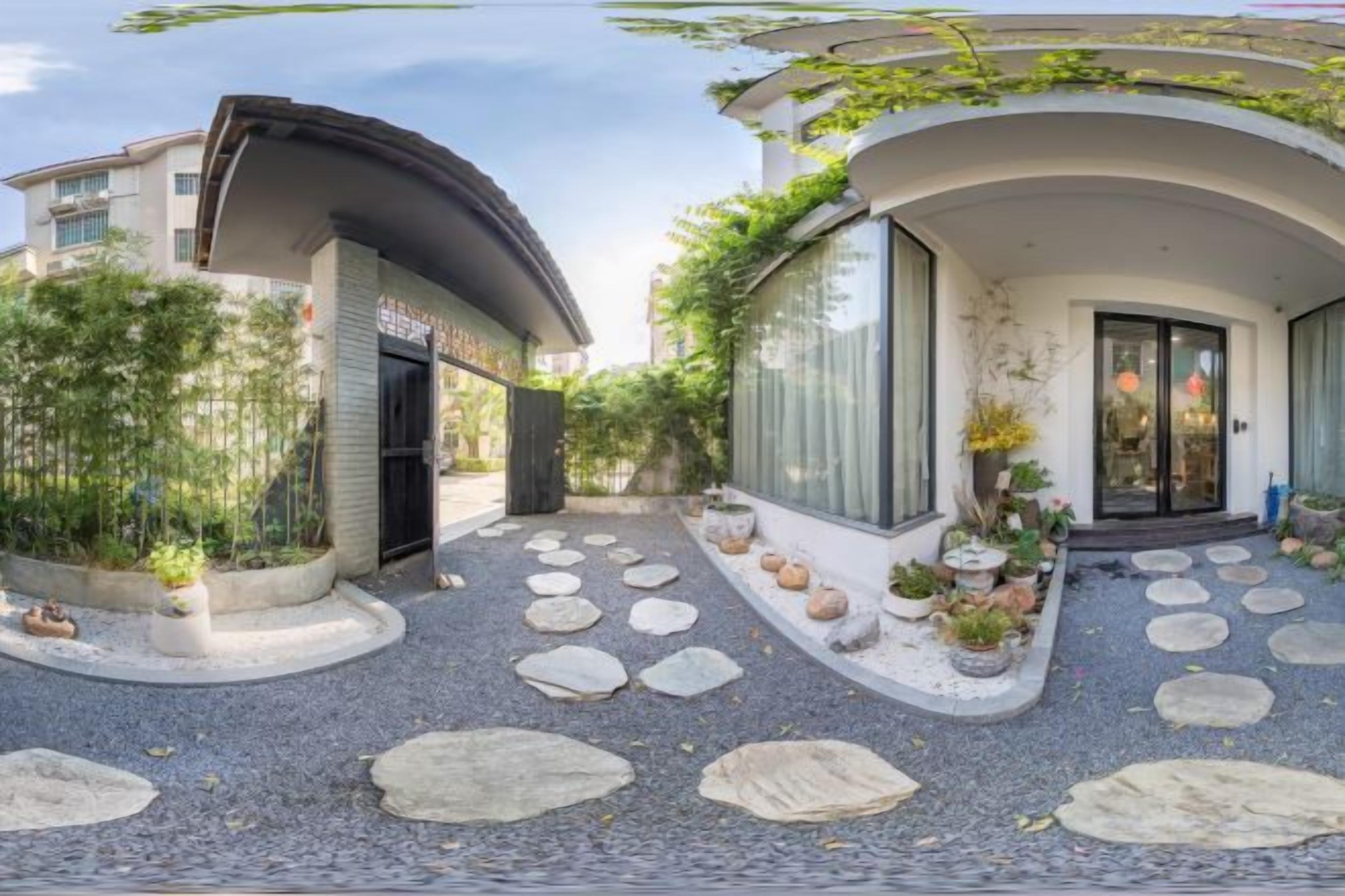 Un pati amb un camí corbat, plantes en testos i l'entrada d'un edifici.