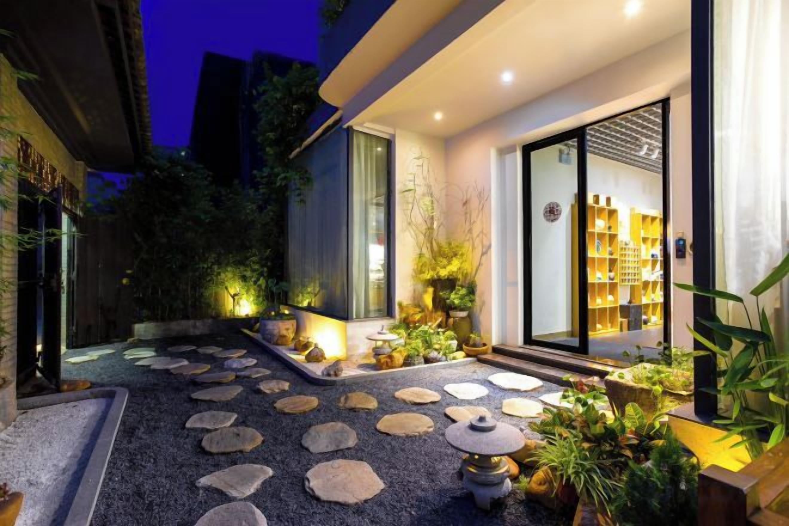 Facciata moderna di un edificio con un vialetto in pietra che conduce a un ingresso con porta in vetro.
