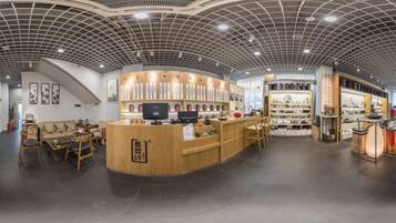 A spacious lobby with a curved reception desk, seating area, and a ceiling with a grid pattern.