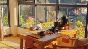Une pièce avec une table en bois, une chaise et une vue dégagée sur l’extérieur grâce à de grandes fenêtres.
