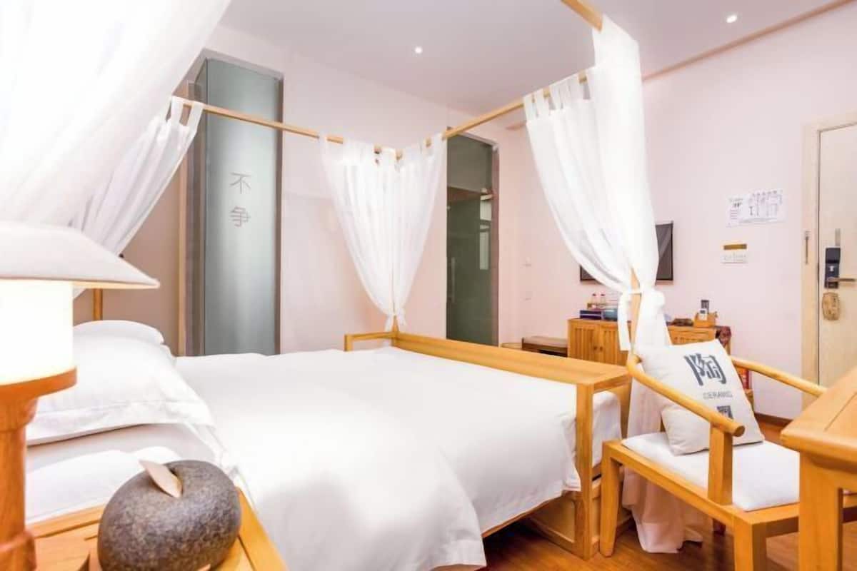 Una habitación con cama, muebles de madera, un objeto de piedra y una pared con texto.