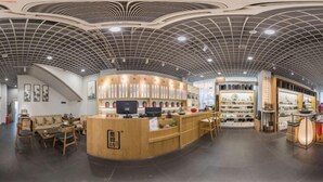 Un intérieur moderne avec un comptoir d’accueil incurvé, un espace salon et des étagères d’exposition.