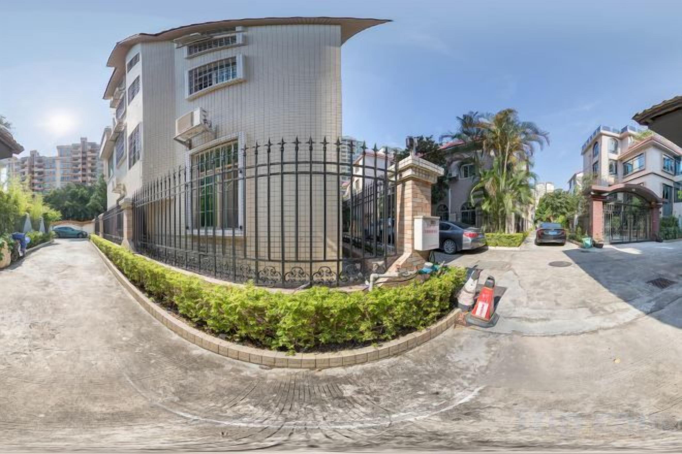 A multi-story residential building with a curved facade, a gated entrance, and a paved driveway.