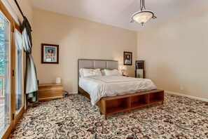 Un dormitorio con una cama grande, un banco de madera, una mesita de noche, una lámpara y un aplique de techo.